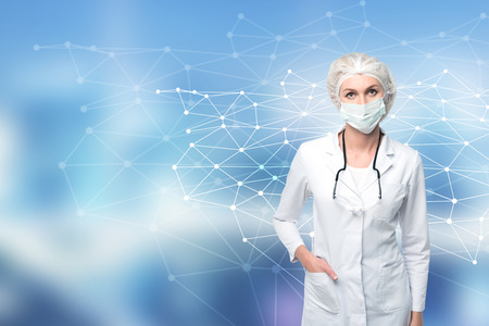 Portrait of a woman doctor standing against a blurred blue background with a molecule model to her side.の写真素材