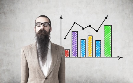 Portrait of a businessman with a long beard standing near a concrete wall with two colorful graphs on it.の写真素材
