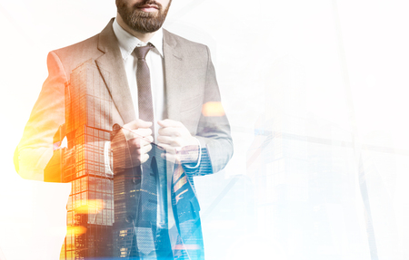 Close up of a bearded businessman in a brown suit standing against a sunny city panorama. Toned image. Double exposure. Mock upの写真素材