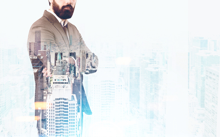 Unrecognizable bearded businessman in is standing with crossed arms against a foggy city panorama. Toned image, mock up, double exposureの写真素材
