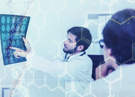 Young bearded doctor is sitting in his office and showing an x ray image to his patient wearing glasses. Chemical formulas in the foreground. Toned image, double exposureの写真素材