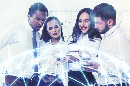 Business team members of diverse ethnicity are brainstorming sitting at a long white table and talking. Network in the foreground. Toned image double exposureの写真素材