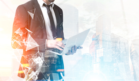 Close up of an unrecognizable businessman standing with a laptop against a foggy city background. Mock up toned image double exposure.の写真素材