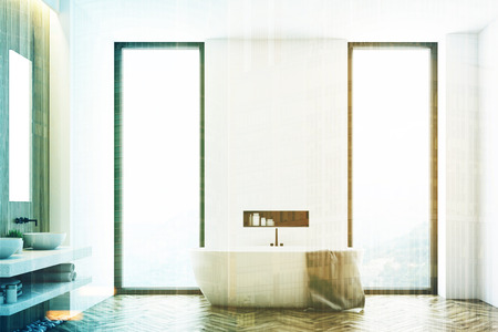 White modern bathroom interior with a white tub standing near a window, a large towel hanging on its side and a shelf with cleaning products in the wall. 3d rendering, mock up, toned imageの写真素材