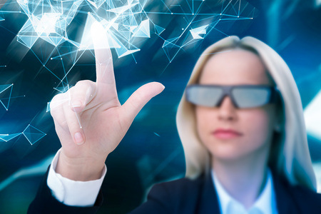 Portrait of a calm businesswoman wearing AR glasses pointing at an abstract blue pattern against a...