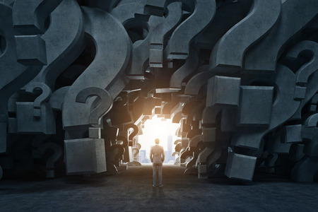 Rear view of a businessman standing in an empty room with gray 3d question marks on the walls. There is a way out near him. Close up. Concept of an answer search. 3d rendering mock upの写真素材