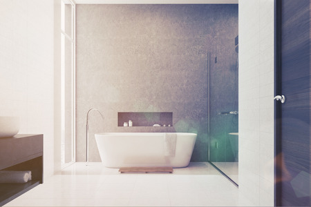 Gray bathroom interior with white tiles used as a decoration element. There is a white tub, a shower with a glass door, a white sink and a large window. 3d rendering mock up toned imageの写真素材