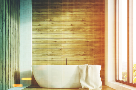 Wooden bathroom interior with a white tub and a towel handing on it and a large window. 3d rendering mock up toned imageの写真素材