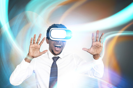 Portrait of a young excited African American businessman wearing VR glasses and smiling. He is...