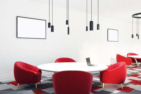 Open office room with a group work area with a large round table and red armchairs. Posters on the wall. 3d rendering mock upの写真素材