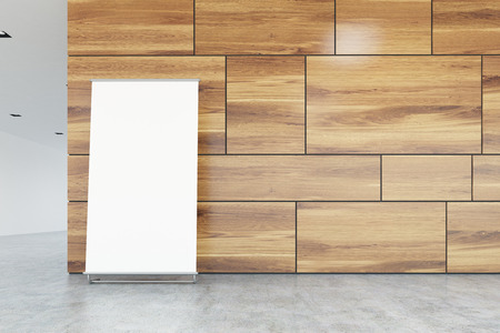 Vertical poster is standing on a gray office floor near a light wooden wall in a lobby. Concept of product placement and advertising. 3d rendering mock upの写真素材