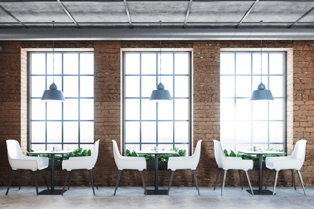 Brick cafe interior with a concrete floor, white chairs and small square tables. Tall windows and original lamps. 3d rendering mock upの写真素材