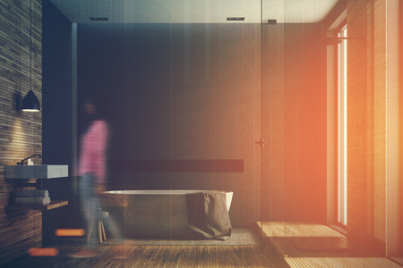 Black and wooden bathroom interior with a wooden floor, tall windows, a round white tub, an angular sink and a glass shower corner. A woman 3d rendering mock up toned image double exposureの写真素材