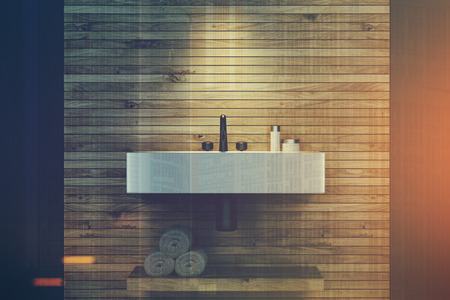 Close up of an angular sink in a wooden and dark gray bathroom interior. There is a wooden shelf with rolled up towels and a round lamp. 3d rendering mock up toned image double exposureの写真素材
