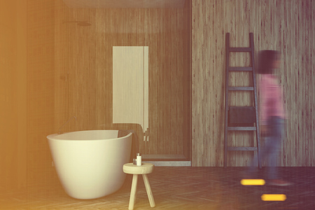 Gray and wooden bathroom interior with a wooden floor, a shower, a ladder and a white tub. A woman. 3d rendering toned imageの写真素材