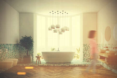 White and green tiles bathroom interior with a large window, a white round tub, two toilets and a...