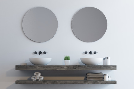 Close up of a double sink standing on a wooden shelf. There are two round mirrors above it and a shelf for towels under it. 3d renderingの写真素材