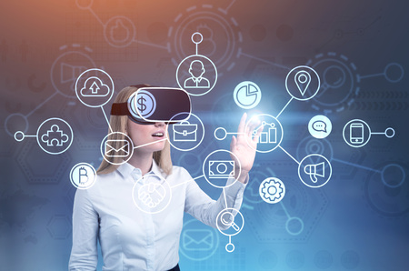 Blonde businesswoman wearing VR glasses interacting with a network interface. A blurred blue...