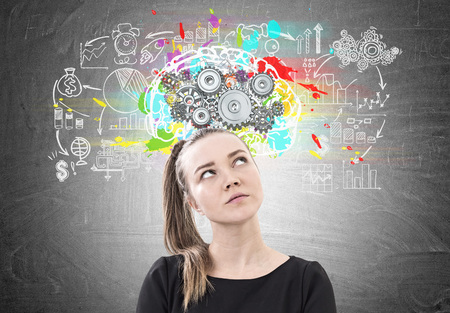 Portrait of a thoughtful young woman wearing a black T-shirt and looking upwards. A blackboard...