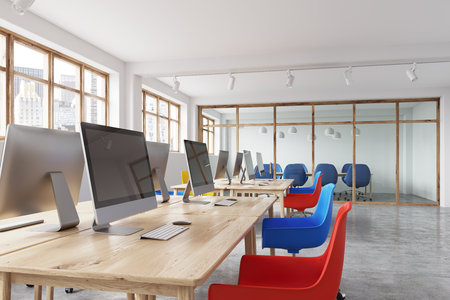 Modern office corner with white walls, a concrete floor, rows of tables with computers on them and blue and red chairs. Close up 3d rendering mock upの写真素材