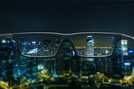 Night cityscape with skyscrapers and city lights as seen through a pair of glasses. Blurred image.の写真素材