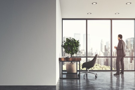 White home office interior with a concrete floor, a panoramic window, and a wooden table with a black chair near it. A man. 3d rendering mock upの写真素材