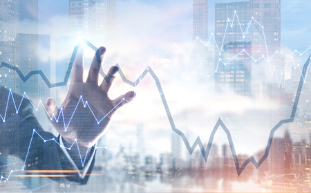 Hand of a businessman wearing a suit interacting with a graphs, a foggy city background. Double exposure toned image mock upの写真素材