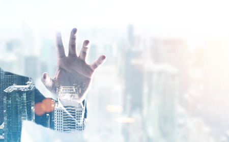Hand of a businessman wearing a suit a foggy cityscape background. Double exposure toned image mock upの写真素材