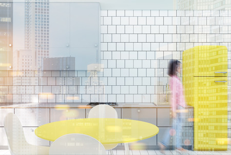 White tiled kitchen interior with a wooden floor, gray countertops, built in appliances, and a yellow fridge. 3d rendering mock up toned image double exposure blurredの写真素材