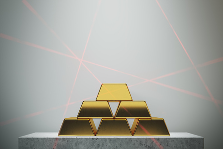 Gold bars pyramid standing against a white wall on a marble table. Concept of savings and economics....