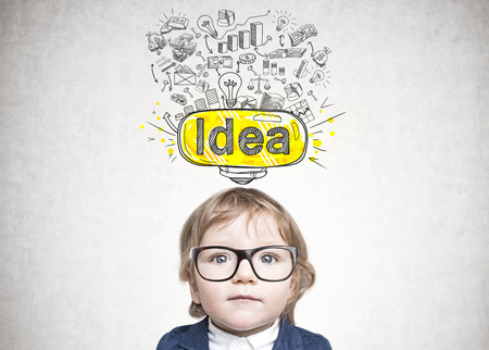 Cute little baby boy wearing glasses and a suit and looking at the viewer. A good idea sketch drawn on a concrete wallの写真素材