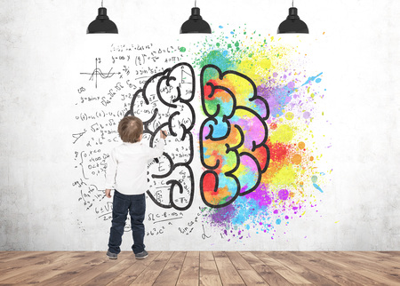 Rear view of a cute little boy wearing a white shirt and dark blue jeans writing or drawing with a...