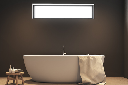 Close up of a white bathtub standing on a wooden floor of a bathroom with dark gray walls and a...
