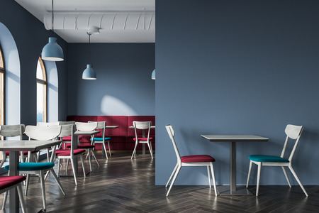 Modern gray cafe interior with a wooden floor, a bar with stools and square tables with blue chairs...