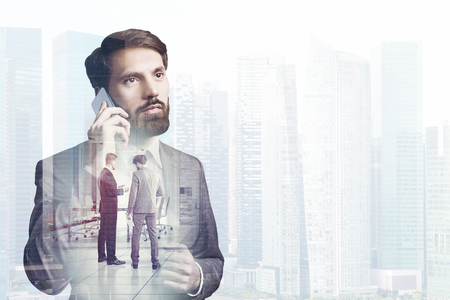 Bearded young businessman talking on his phone in a foggy city. Business communication concept. Mock up double exposureの写真素材