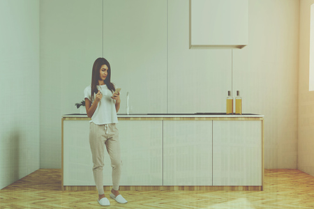 White kitchen interior with white and countertops, a wooden floor and a window. Young woman standing in the centre. 3d rendering mock up toned image double exposureの写真素材