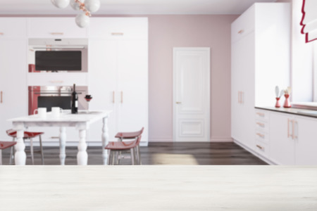 Luxury kitchen interior with a wooden floor, white countertops with built in appliances and a marble table with red chairs. A door 3d rendering blurredの写真素材