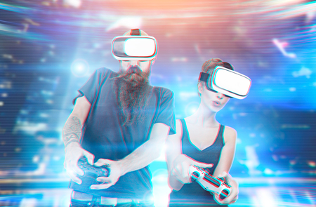 Bearded young guy and a pretty girl playing playing virtual reality games in a futuristic...