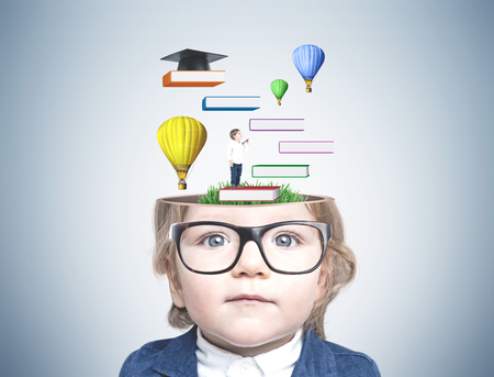 Portrait of a cute little baby boy wearing glasses and a suit and looking to the camera. A concrete wall background with a colorful education sketchの写真素材