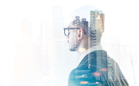 Young businessman in glasses looking at a city. Business leadership and decision making concept. Toned image double exposure mock upの写真素材