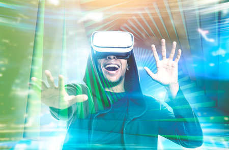 Happy young African American man wearing a hoodie and VR glasses. Concept of the future technology....