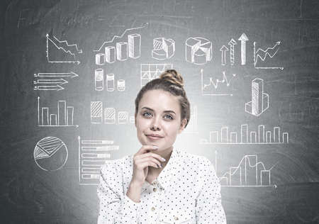 Portrait of a young woman wearing a white dotted shirt and sitting with her hand on the chin. She is looking away and dreaming. Types of graphsの写真素材