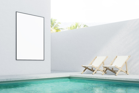 Resort or private pool with blue green water surrounded by a white wall. Tropical scenery. Beach chairs and a blank poster on the wall. Concept of rest and relaxation. 3d rendering mock upの写真素材