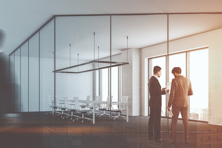 Business people talking near a glass and metal office conference room with panoramic windows and a long white table with chairs around it. 3d rendering mock up toned image double exposure blurredの写真素材