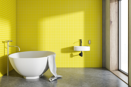 Round white bathtub standing in a yellow bathroom inteiror with a round sink and a loft window. A concrete floor. A cozy home concept 3d rendering mock upの写真素材