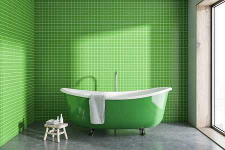 Green bathtub with a towel hanging on it standing on a concrete floor of a minimalistic bathroom. A small chair. 3d rendering mock upの写真素材