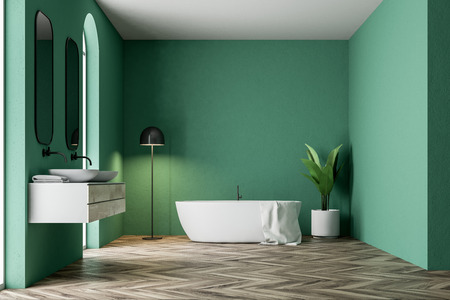 Minimalistic green bathroom interior with a white bathtub, a towel hanging on it, a double sink, a potted tree and a lamp in the corner. 3d rendering mock upの写真素材
