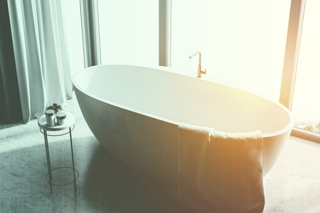 Modern bathroom interior with a marble floor, a panoramic window with a mountain view and a white bathtub. A top view. 3d rendering toned imageの写真素材