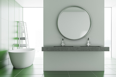 Round mirror hanging above a double sink in a modern bathroom with white and green tile walls and panoramic windows. 3d renderingの写真素材