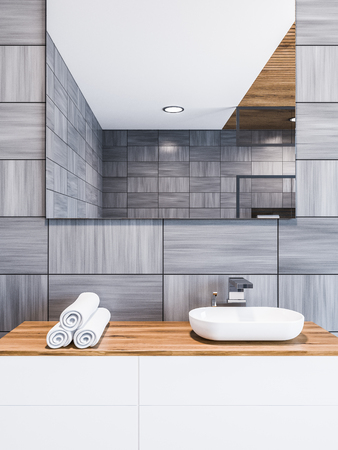 White sink on a wooden counter with rolled towels and a square mirror hanging above it in a Scandinavian style gray wooden wall loft bathroom interior. Spa Hotel. Close up. 3d rendering mock upの写真素材